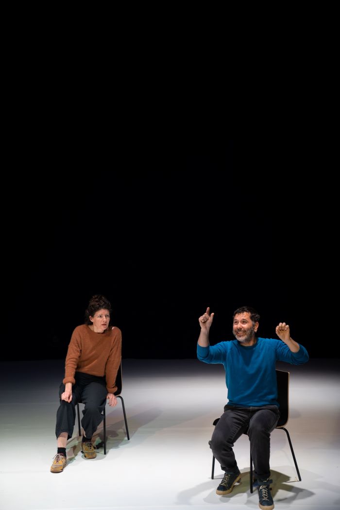 Deux personnages assis sur leux chaises face au public discutent.